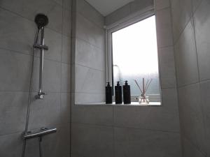 ein Badezimmer mit Dusche und Flaschen auf einem Regal in der Unterkunft City Convenience, Calm Comfort-- A Stylish One-Bedroom Retreat Just 3 Stops from the Heart of the City in Edinburgh