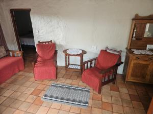 ein Wohnzimmer mit zwei roten Stühlen und einem Tisch in der Unterkunft Melville Guesthouse & Contractors Lodge in Lichtenburg