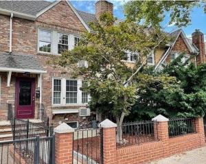 a brick house with a red door and a fence at The Plateau Chateau in Queens