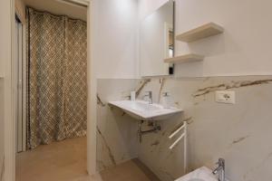 Un baño blanco con lavabo y espejo. en GOLDEN LUXE - New Style in Forte dei Marmi Private Parking, en Forte dei Marmi