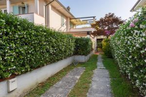 Un camino de jardín frente a un edificio con arbustos. en GOLDEN LUXE - New Style in Forte dei Marmi Private Parking, en Forte dei Marmi