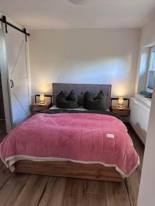 Un dormitorio con una cama grande con una manta rosa. en Luxury-Wellnessresidence- Altes Kapitänshaus, en Dranske