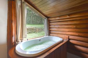 a bath tub in a room with a window at Pousada Cachoeira da Barra in Cunha
