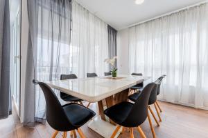 ein Esszimmer mit einem weißen Tisch und schwarzen Stühlen in der Unterkunft Flex SelfCheckIns 100 - Zagreb - 2 Bedrooms - Parking - Loggia in Velika Mlaka