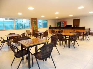 Un restaurante con mesas y sillas de madera en una sala. en Porto Beach Conforto e Lazer a 200m do B Park, en Aquiraz