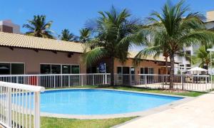 una piscina frente a un edificio con palmeras en Porto Beach Conforto e Lazer a 200m do B Park, en Aquiraz
