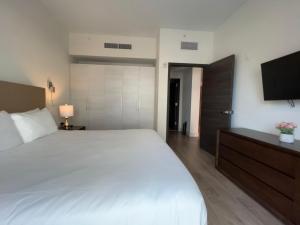 a bedroom with a large white bed and a flat screen tv at A Fantastic apart with balcony and partial view of the beach 4 Px in Hollywood +28 photos