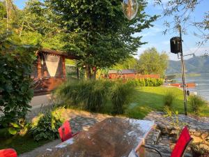 a table and chairs in a garden with a lake at Vikendica Vilcek in Mali Zvornik +79 photos