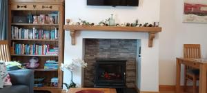 un salon avec une cheminée avec une étagère au-dessus dans l'établissement Bovinda Cottage - By the Beach, Bettystown, à Bettystown