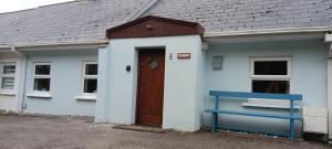 une maison blanche avec une porte marron et un banc bleu dans l'établissement Bovinda Cottage - By the Beach, Bettystown, à Bettystown 11 autres photos