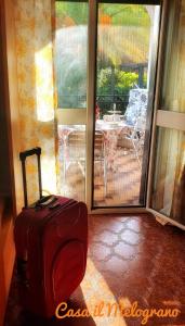 a red suitcase sitting on the floor in front of a door at Casetta il Melograno Cozy two-room apartment to the Sea in Villaggio Mosè +11 photos