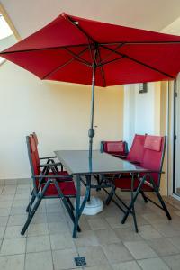 einen Tisch und Stühle mit einem roten Regenschirm in der Unterkunft Spacious Apartment with Huge Terrace and Swimming Pool in Lagos + 84 Fotos