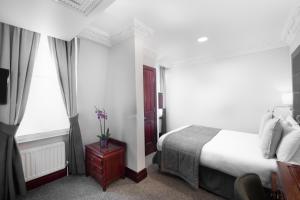 a hotel room with a bed and two windows at Gem Fitzrovia Hotel in London