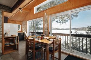 une salle à manger avec une table et quelques fenêtres dans l'établissement Cottage on Sarrazin lake & Sauna - Lake Panorama, à Sainte-Lucie-de-Doncaster