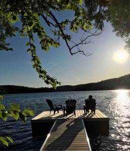 un homme assis sur un quai sur un lac dans l'établissement Cottage on Sarrazin lake & Sauna - Lake Panorama, à Sainte-Lucie-de-Doncaster