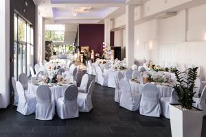 una habitación llena de mesas y sillas blancas con mesas y sillas blancas en Hotel George, en Nadarzyn