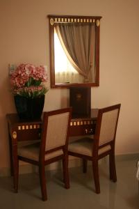 a table with two chairs and a mirror and a vase with flowers at Crown Hotel Juba in Juba