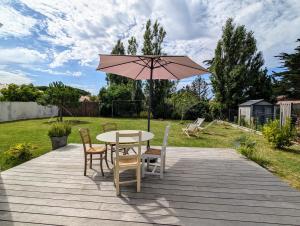 a patio with a table and chairs and an umbrella at Maison familiale avec jardin a deux pas de l'océan in Préfailles