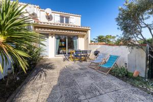 a patio with chairs and a table in front of a house at Le 5 Mimosas - Plage à 600m garage in Saint-Jean-de-Monts