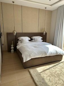 a bedroom with a large bed with white sheets and pillows at Three Bedrooms Smart Access Compound - شقة انيقة ثلاث غرف كمباوند مدخل ذكي in Dammam +14 photos