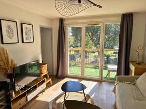 a living room with a tv and a large window at L'Eclat Terrasse - Piscine - Tennis in Ondres