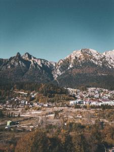 a town in front of a mountain range with snow at Moon Montana Busteni in Buşteni