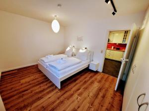Un dormitorio con una cama blanca y suelos de madera. en Ferienwohnung Bodenseeglück, en Weißensberg