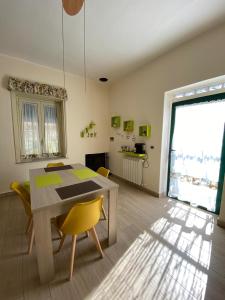 a dining room with a table and yellow chairs at Casa Vacanze Magistro in Patti