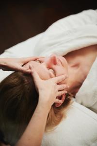 a woman laying in bed with her hands on her face at Sheraton Sopot Hotel in Sopot