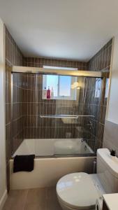 a bathroom with a tub and a toilet and a sink at ENTIRE 2 BEDROOM APARTMENT by UW RESEARCH PARK - PS5 in Waterloo +10 photos