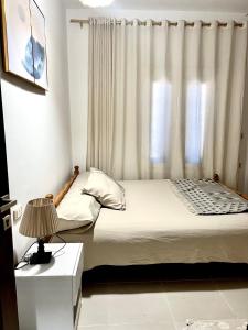 a bedroom with a bed with a window and a lamp at Rosiland Villa - Marsa Matrouh in Marsa Matruh