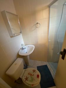 a bathroom with a toilet and a sink and a shower at Enseada Malibu perto da praia, lazer e conforto! in Guarujá +18 photos