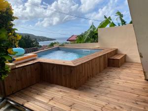 a swimming pool on a wooden deck with a wooden floor at Les Alizés 3 chambres et piscine Les Anses d Arlet in Les Anses-dʼArlets