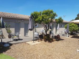 a patio with a tree and chairs and umbrellas at Studio climatisé île naturiste du Levant in Hyères