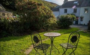 two chairs and a table in a yard at Calebs Cottage- Solva harbour in Solva