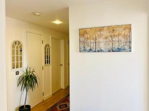 a hallway with a painting on the wall and a plant at North Greenwhich Homestay in London