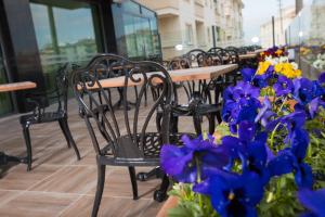 a row of tables and chairs with purple and blue flowers at Görükle Güler Park Hotel in Gorukle