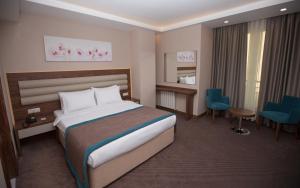 um quarto de hotel com uma cama grande e cadeiras em Görükle Güler Park Hotel em Gorukle