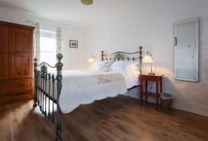 a bedroom with a bed with white sheets and a window at Ballymultimber Cottages - traditional cottages on the Causeway Coast in Limavady