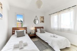 two beds in a white room with a window at Limnaria Gardens Beautiful Apartment by VICHY in Paphos