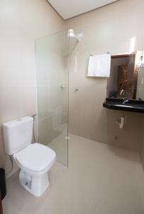 a bathroom with a toilet and a glass shower at Pousada Calugy in Jardim +18 photos