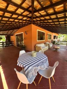 a patio with a table and white chairs at Casa aconchego Secretário in Araras Petropolis