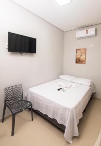 a bedroom with a bed and a chair and a flat screen tv at Pousada Calugy in Jardim