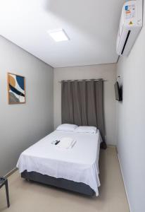 a bedroom with a white bed and a window at Pousada Calugy in Jardim