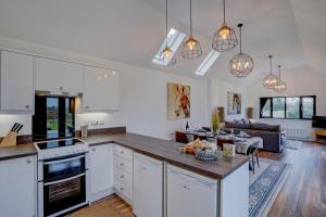 a kitchen with white cabinets and a living room at The Old Stable by Winterton Cottages in Hemsby +10 photos