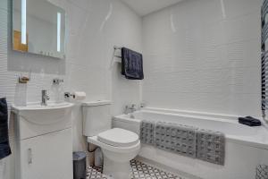 a white bathroom with a toilet and a sink at The Old Stable by Winterton Cottages in Hemsby