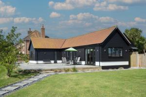 a black house with a patio and a house at The Old Stable by Winterton Cottages in Hemsby