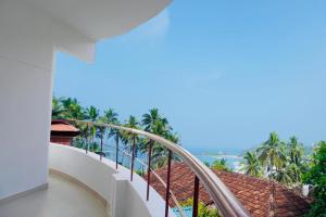 a balcony with a view of the ocean and palm trees at Udaya Hotel in Kovalam