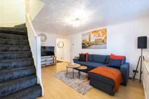 a living room with a blue couch and stairs at SionStays - Honeysuckle Court - Close to City Centre! in Peterborough