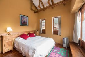una camera da letto con un grande letto bianco con cuscini rossi di SAUCE Hotel Boutique a Ollantaytambo